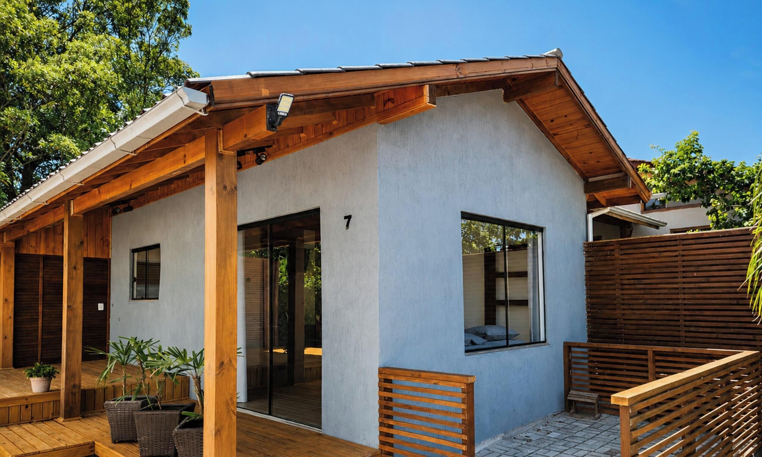 Una casa moderna con terraza de madera, porche cubierto y el número 7 en la pared.
