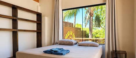 Un dormitorio con una cama grande, cabecera de madera y vista a zonas verdes.
