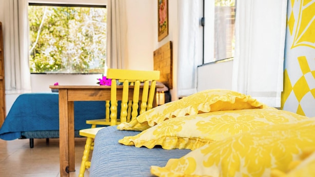 Une chambre à coucher comprenant un lit, une chaise, une table et une fenêtre donnant sur un paysage verdoyant.