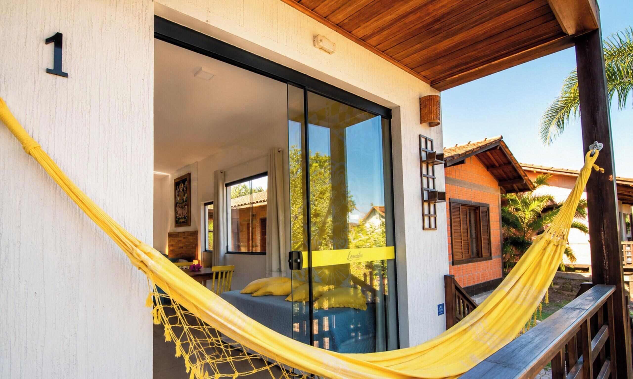 A room with a bed, a hammock, and a sliding glass door leading to an outdoor area.