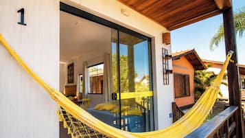 A room with a bed, a hammock, and a sliding glass door leading to an outdoor area.