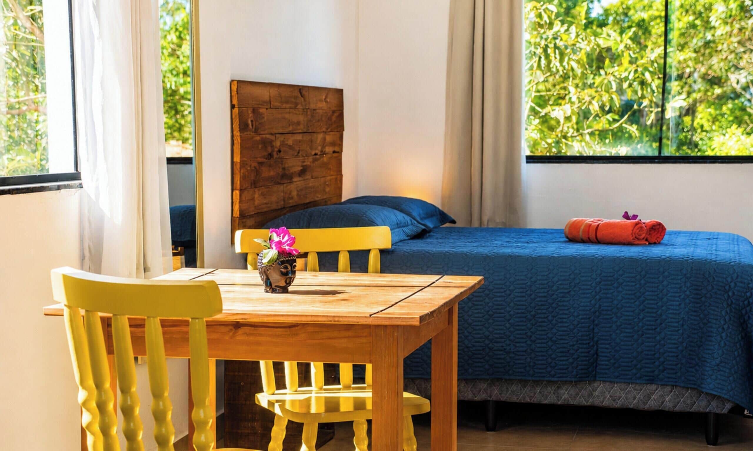 A room with a bed, a wooden table, and chairs.