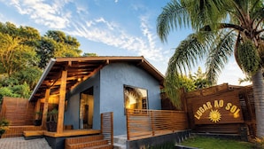Une maison moderne avec un toit en pente, une terrasse en bois et une enseigne indiquant « LUGAR AO SOL ».