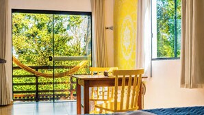 Une pièce avec une table en bois, une chaise jaune et un hamac.
