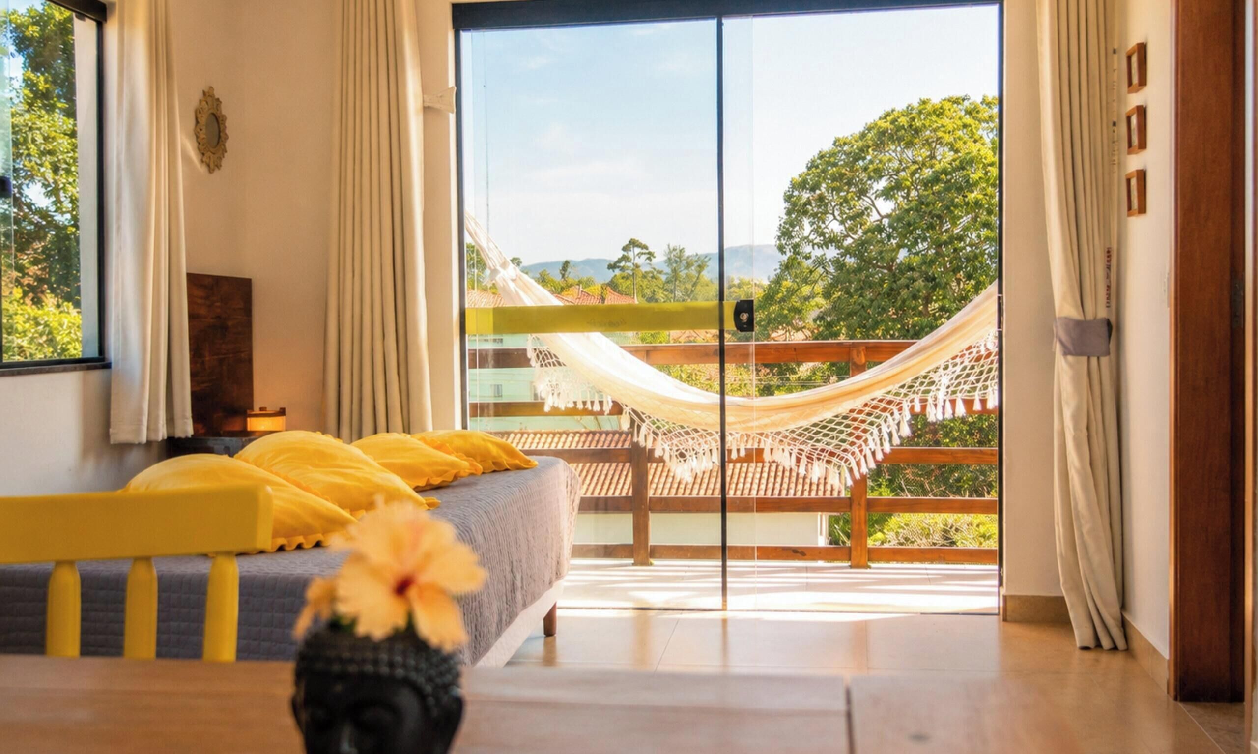 A bedroom with a bed, a hammock, and a view of the outdoors.