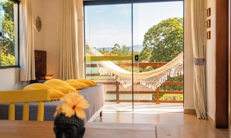 A bedroom with a bed, a hammock, and a view of the outdoors.