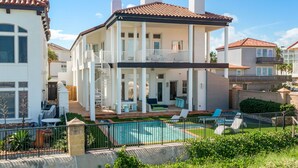 Une maison à deux étages dotée d’un balcon, d’une piscine et d’un espace patio.