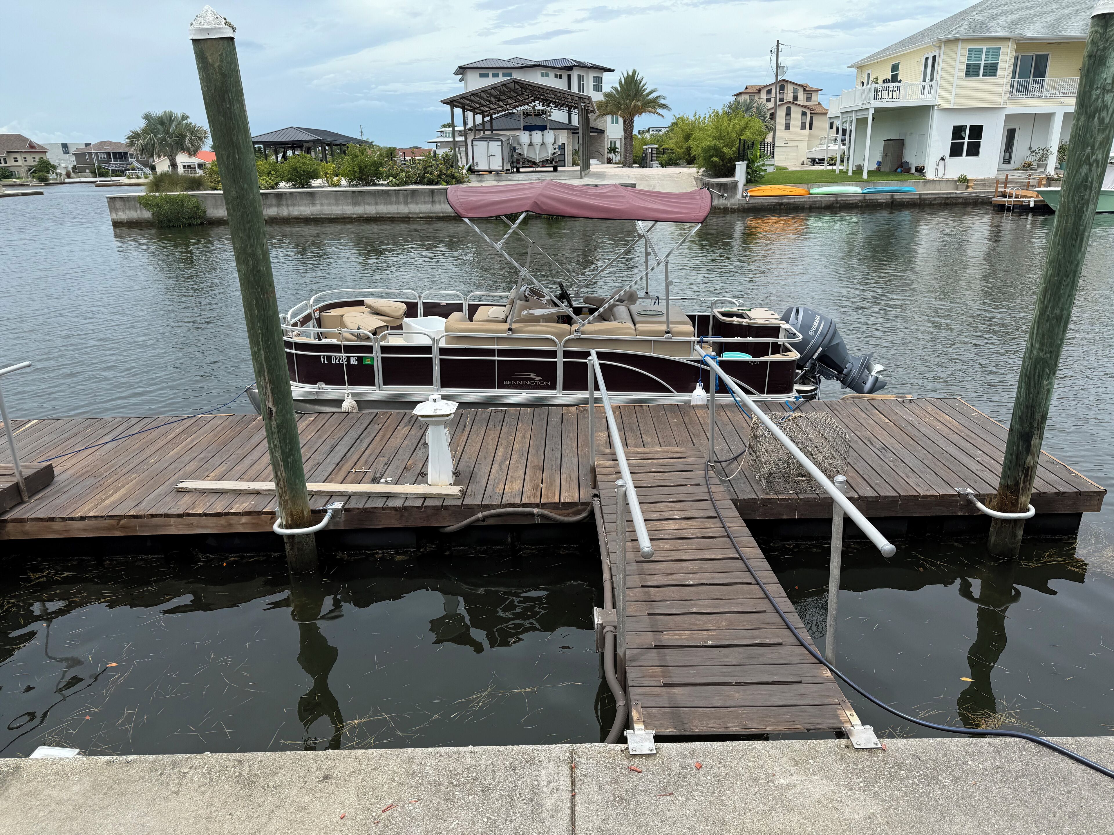 A boat docked at a wooden pier with a covered seating area and a water pump.