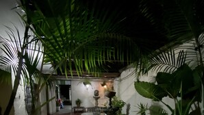 A courtyard with potted plants, a stone fountain, and a seating area.