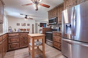 A modern kitchen with wooden cabinets, stainless steel appliances, and a ceiling fan.