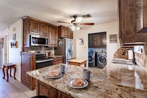 A kitchen with granite countertops, wooden cabinets, a microwave, oven, and a ceiling fan. - MP Ranch - 20min from Waco/Magnolia/Baylor (Waco)