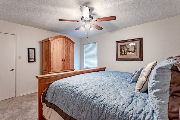 A bedroom with a wooden bed, a ceiling fan, a window with blinds, and a framed picture on the wall. - MP Ranch - 20min from Waco/Magnolia/Baylor (Waco)