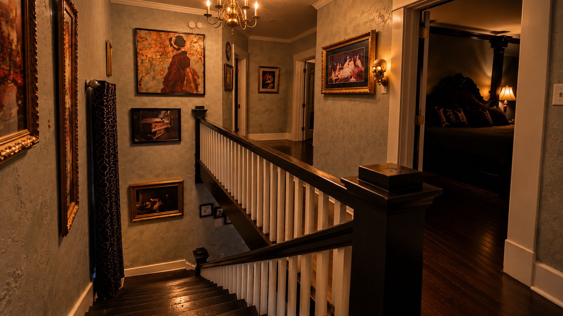 A staircase with a handrail, flanked by framed artwork and a chandelier.