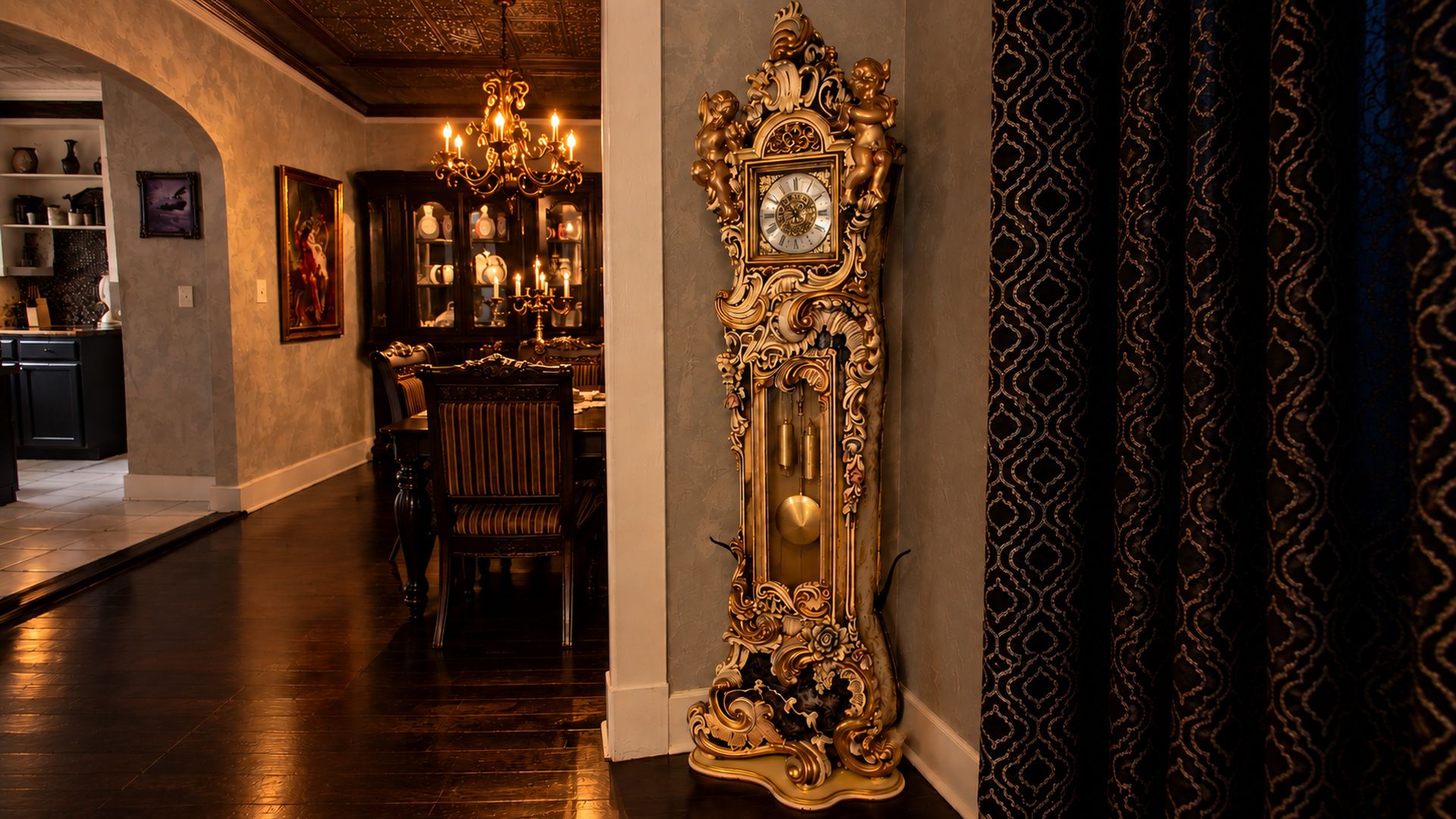 A grand hallway with a large ornate clock, a chandelier, and a dining area with a table and chairs.