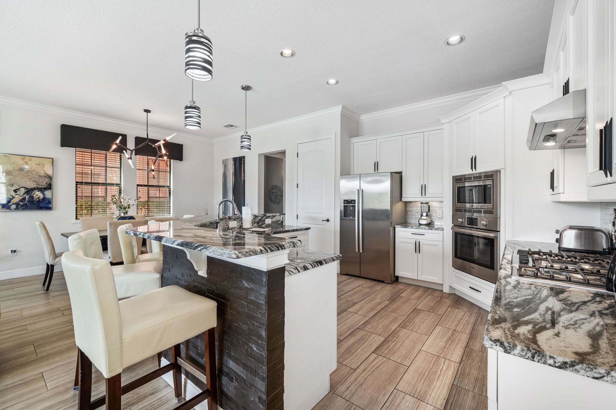A modern kitchen with white cabinets, stainless steel appliances, and a marble island.