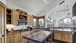 A spacious kitchen with wooden cabinets, a large island, and a view of the outdoors through the windows.