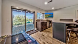 Una cocina moderna con una isla grande, armarios de madera y vista a un lago a través de puertas corredizas de vidrio.