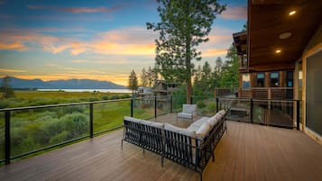 Une terrasse en bois, agréée de mobilier d’extérieur, qui offre une vue imprenable sur un paysage magnifique, avec des montagnes et un ciel dégagé.