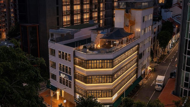 A multi-story hotel with a rooftop terrace, a sign indicating 'KLP,' and a street view with a parked truck. - Aura Hotel Mackenzie (Singapore)