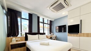 A modern hotel room with a large bed, a desk, a chair, a TV, and a window with curtains. - Aura Hotel Mackenzie (Singapore)