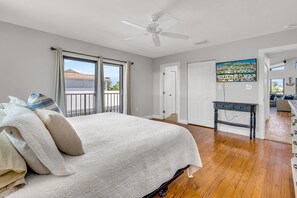 Relax in this serene bedroom with a large bed, ceiling fan, and scenic view through the large window.