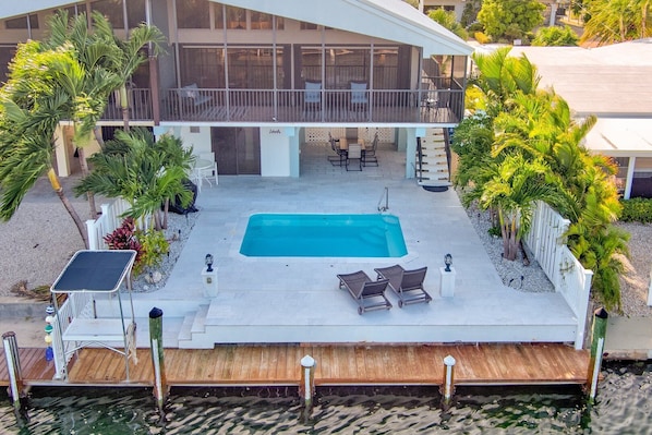 Relax by the pool surrounded by lush greenery and palm trees.