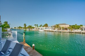Enjoy waterfront views from this property, featuring a dock with lounge chairs and palm trees.
