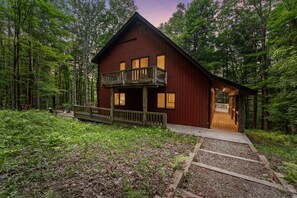 A two-story cabin with a balcony, surrounded by a forest. - ★ Private Hideaway w/Hot Tub & Wood Fireplace- Stylish & Serene - Hike from Cabin! ★ (Ellicottville)