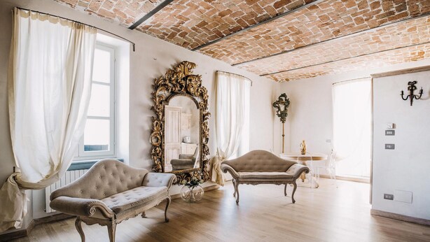 A spacious room with two upholstered sofas, a large ornate mirror, and a brick ceiling.