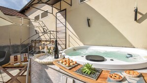 A hot tub with a table set for a meal, including bread and a bottle of wine, and a staircase leading to an upper level.