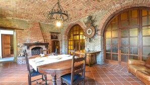 A rustic dining area with a brick fireplace, wooden table, and chairs.