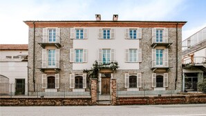 A two-story building with a stone facade, multiple windows with shutters, and a central entrance with a gate.
