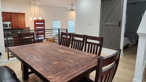 A dining area with a wooden table and chairs, a kitchen in the background, and a sliding barn-style door leading to a bedroom. - Downtown Stay in East Austin @ 12th Street (Austin)