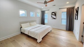 A bedroom with a bed, ceiling fan, windows, and artwork on the walls. - Downtown Stay in East Austin @ 12th Street (Austin)