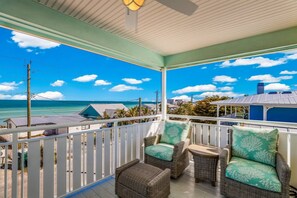 A covered outdoor area with wicker furniture and a view of the ocean. - Reel Deal: Water Views, Elevator, Pool by Anna Maria Life Vacation Rentals (Anna Maria)