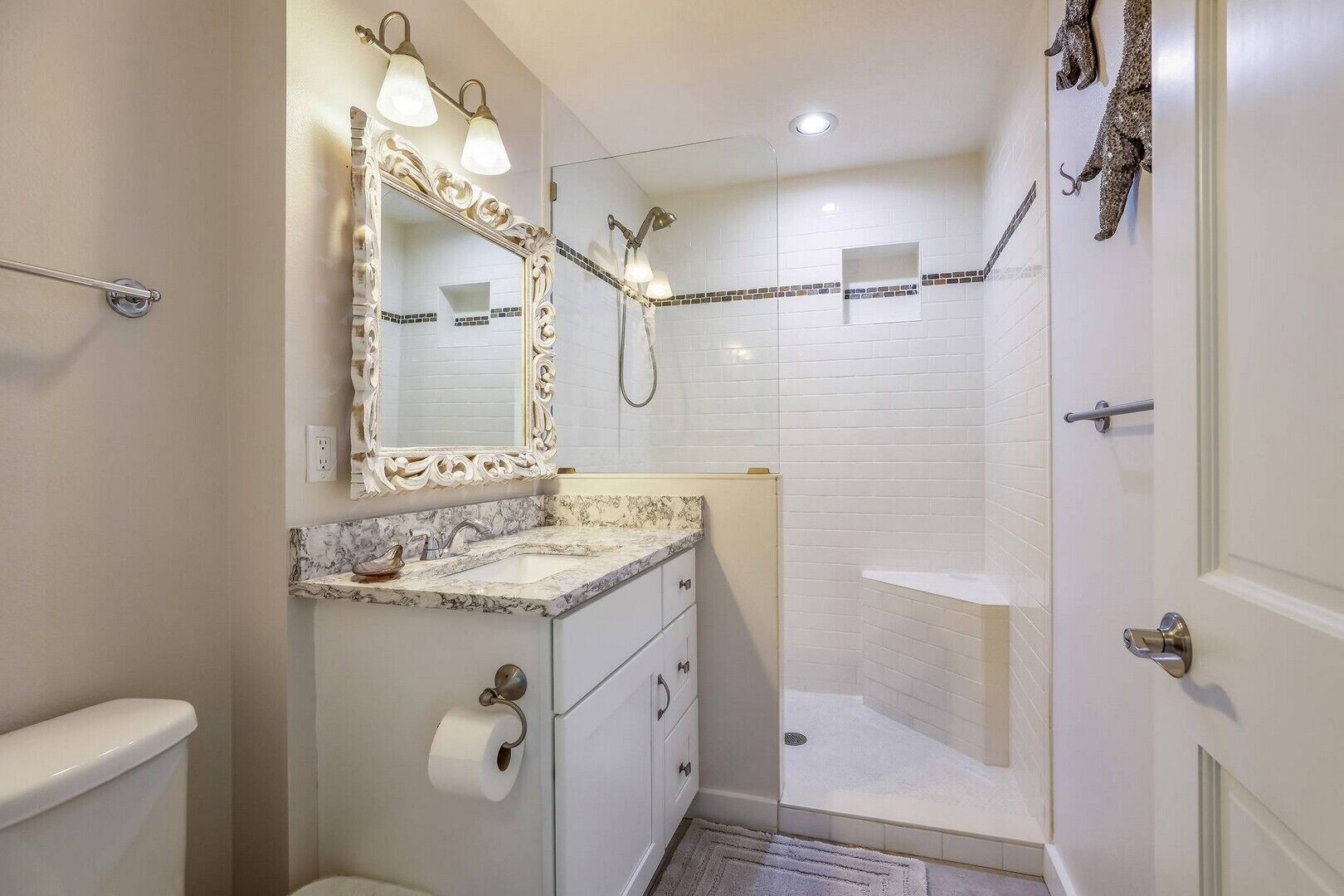 Une salle de bain avec un lavabo en marbre, un grand miroir avec éclairage, une douche et des toilettes.