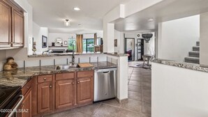 Una cocina amplia con encimeras de granito, armarios de madera y lavavajillas integrado.