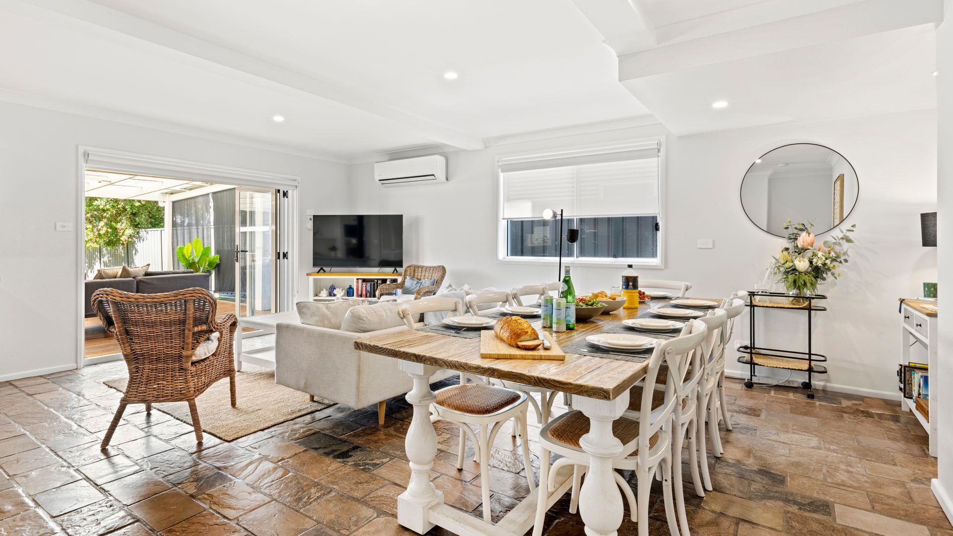 A spacious dining area with a large table set for four, surrounded by white chairs.