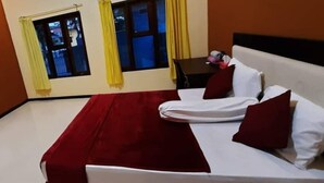 A hotel room with a bed, two windows with curtains, a table with a chair, and an air conditioning unit on the wall. - St.ketapang 2 homestay  (Banyuwangi)