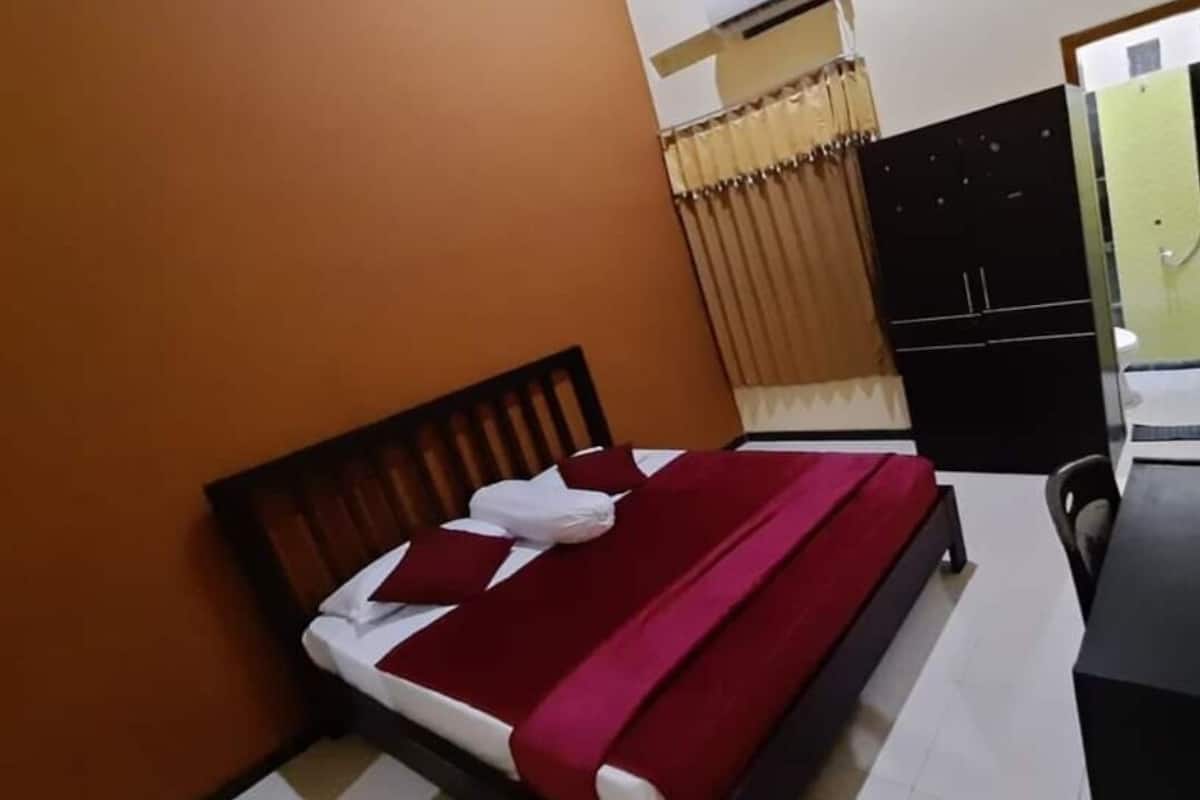 A hotel room with a bed, a desk, and a wardrobe.