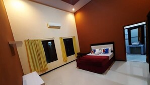 A bedroom with a bed, curtains, a window, and a small table. - St.ketapang 2 homestay  (Banyuwangi)