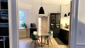 Ett modernt kök med matplats, med bland annat ett fiskbensmönstrat trägolv, en köksö och hängande lampor.