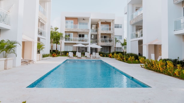 Un hôtel moderne doté d’une piscine centrale, de nombreux balcons et d’espaces de détente en plein air.