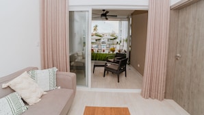 Un salon moderne avec un canapé, une table basse et une vue sur un patio extérieur comprenant une piscine et des chaises.
