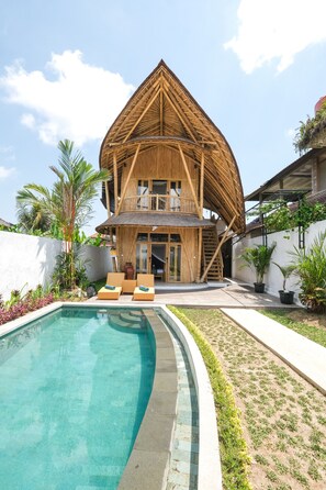 Une grande maison en bois à plan ouvert, dotée d’une piscine et d’un espace salon extérieur.