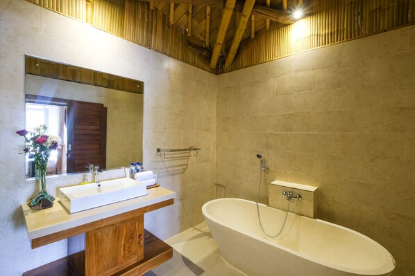 A bathroom with a freestanding bathtub, a vanity with a mirror, and a wooden cabinet.