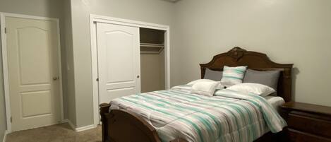 A bedroom with a bed, a dresser, and a closet.