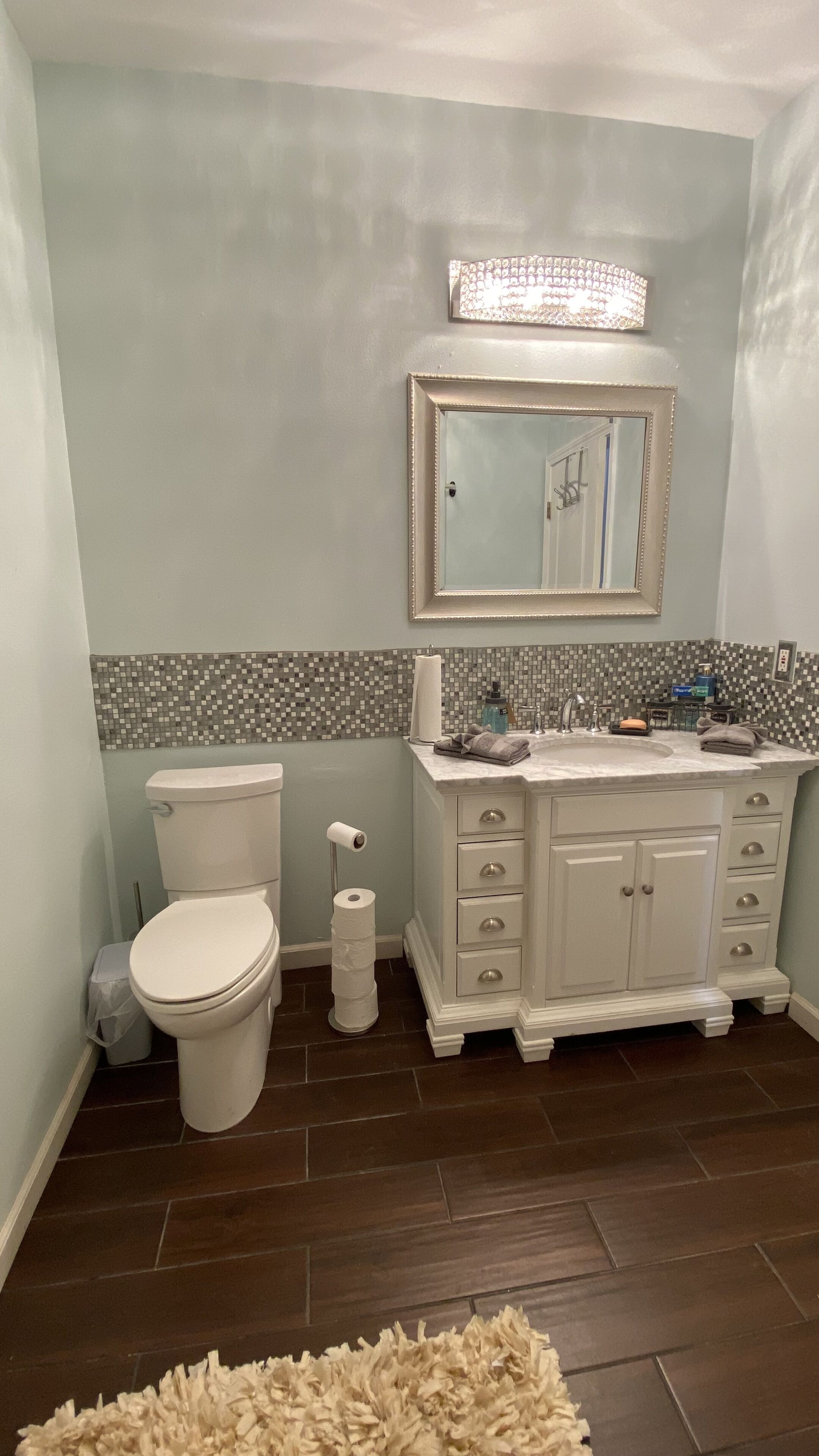 A bathroom with a toilet, sink, and mirror.