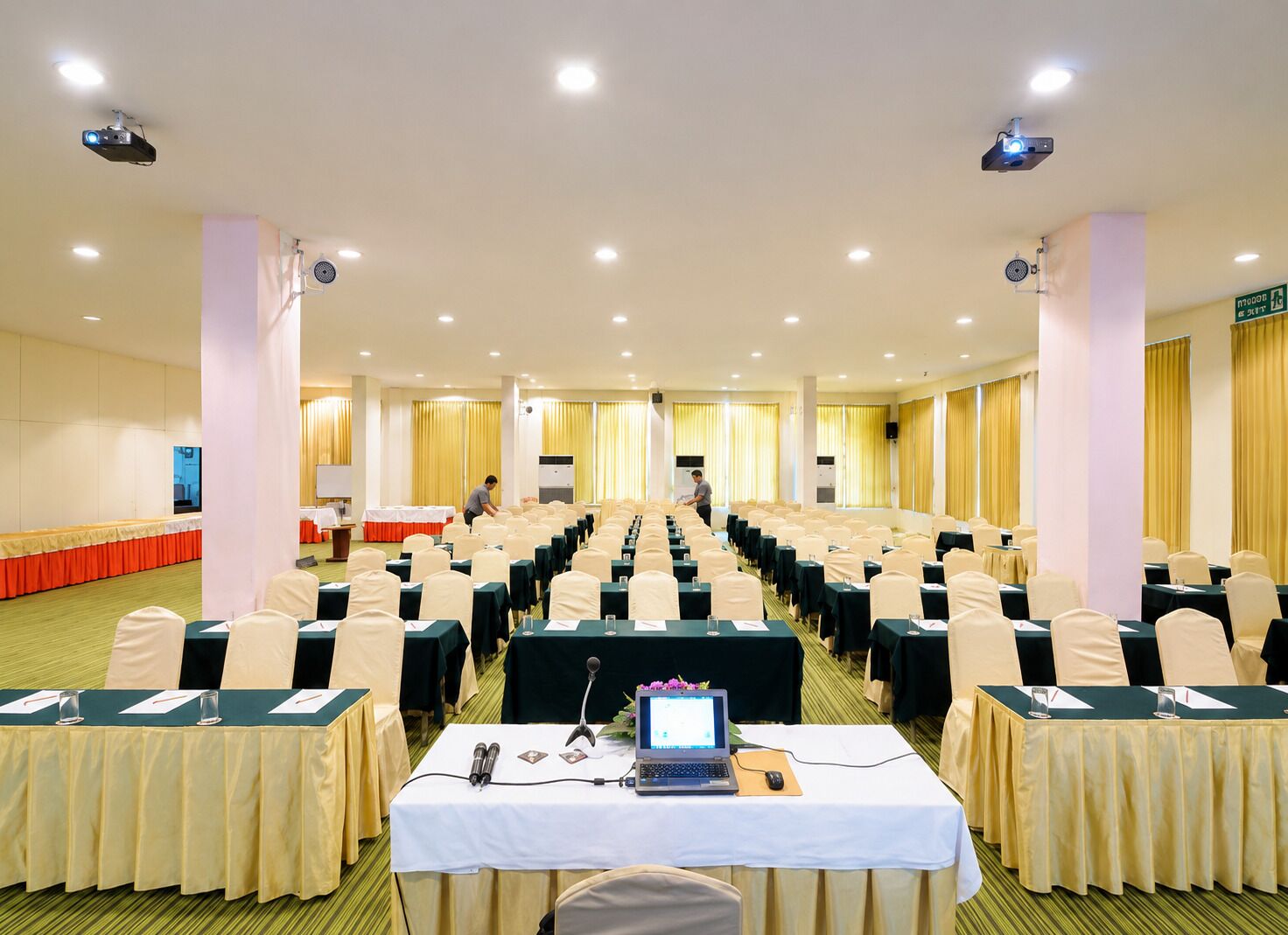 A conference room with rows of tables, chairs, and a podium.