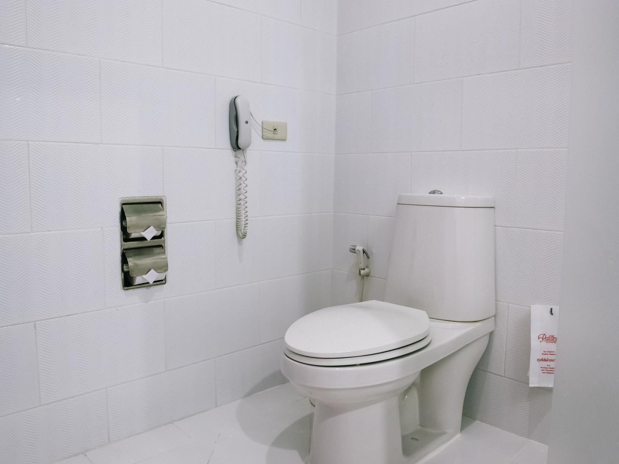 A white toilet with a footrest, a paper towel dispenser, and a hand dryer.